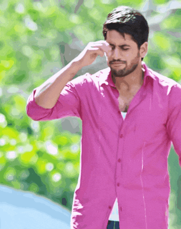 a man in a pink shirt wipes his nose