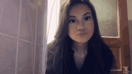 a woman with long hair is standing in front of a door looking at the camera