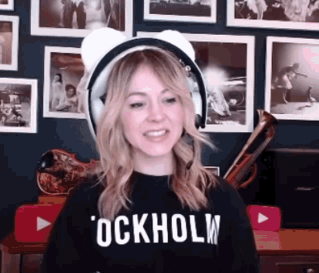 a woman wearing headphones and a black shirt that says ockholw is smiling .