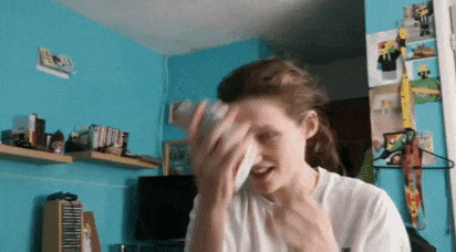 a woman wipes her face with a napkin in a room with a blue wall