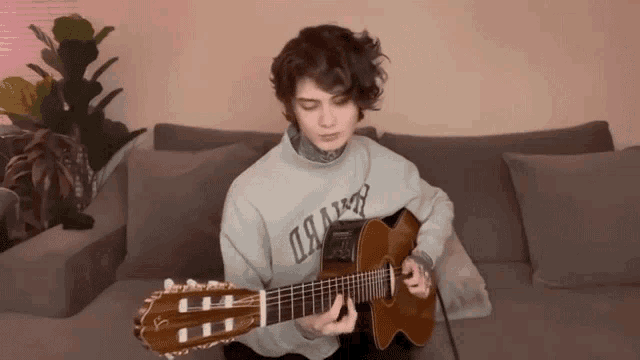 a person playing a guitar with a sweater that says oaam