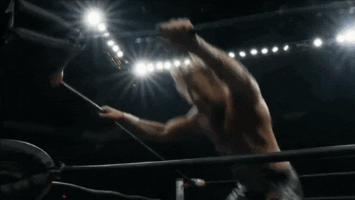 a wrestler is doing a handstand in a wrestling ring in front of a crowd .