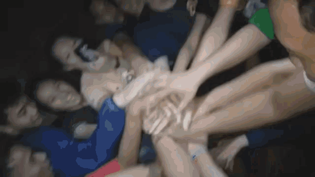 a group of people put their hands together in a huddle
