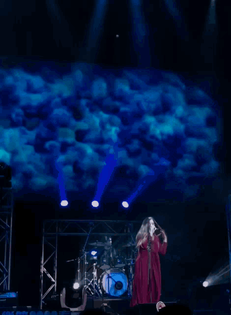 a woman in a red dress singing into a microphone on stage