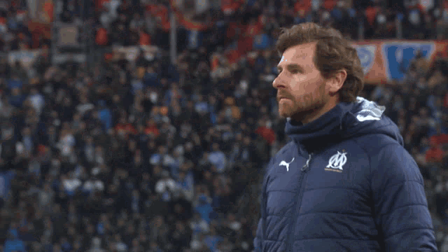 a man wearing a blue jacket with a puma logo on it