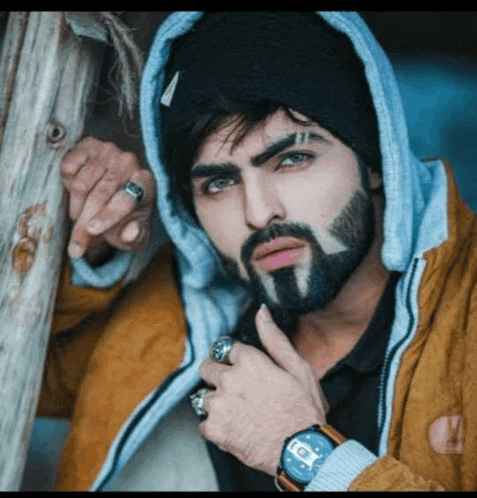 a man with a beard is wearing a watch and a ring on his finger .