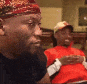 a man wearing a bandana is sitting next to another man wearing a hat .
