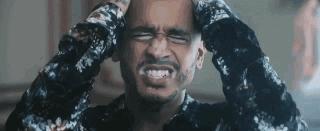 a man with a beard is making a funny face while holding his head .