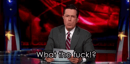 a man in a suit and tie is holding a piece of paper and says what the fuck ?