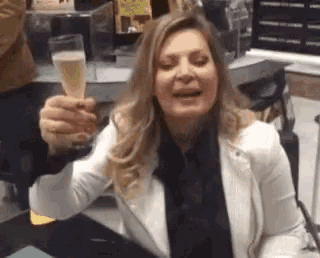 a woman in a white jacket is holding a glass of champagne .