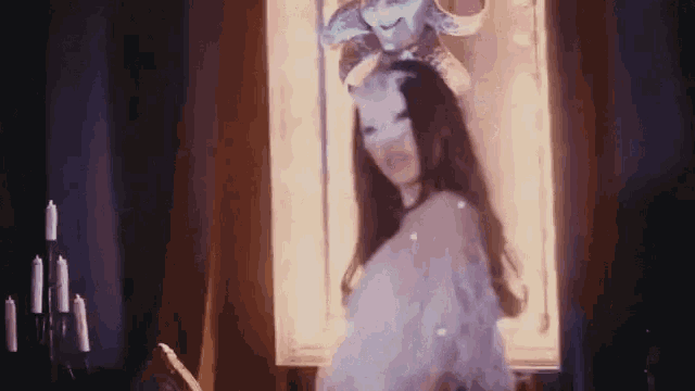 a woman is wearing a mask and standing in front of a window .