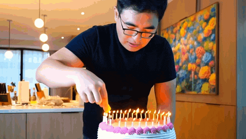 a man wearing glasses is cutting a birthday cake with candles
