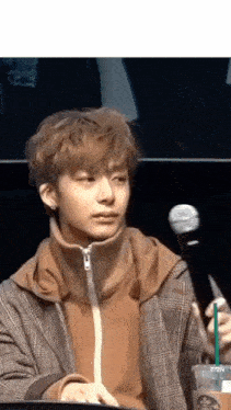 a young man is sitting at a table with a microphone and a starbucks cup .