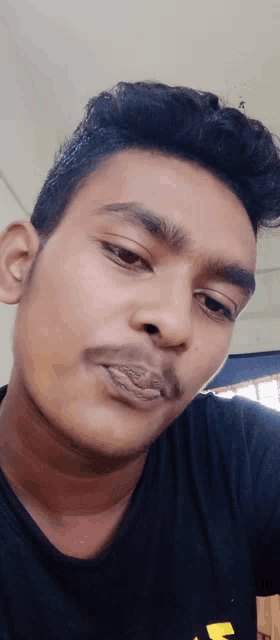 a close up of a man 's face with a black shirt that has the letter s on it