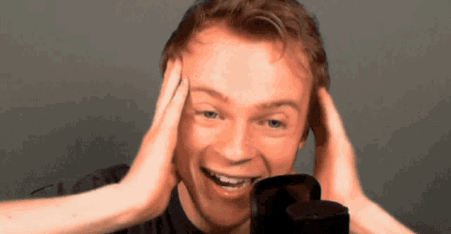 a man with his hands on his head is smiling for the camera