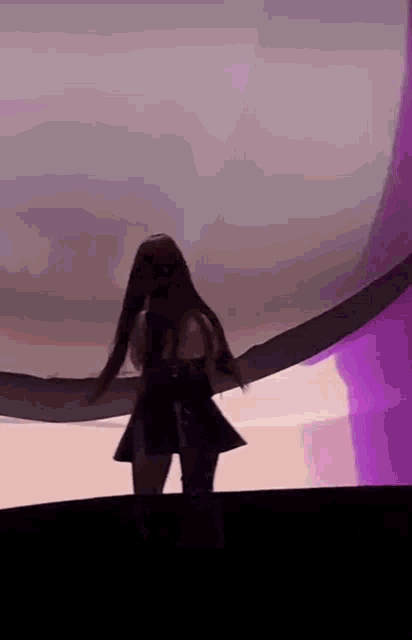 a woman with long hair is standing on a stage in front of a purple light .