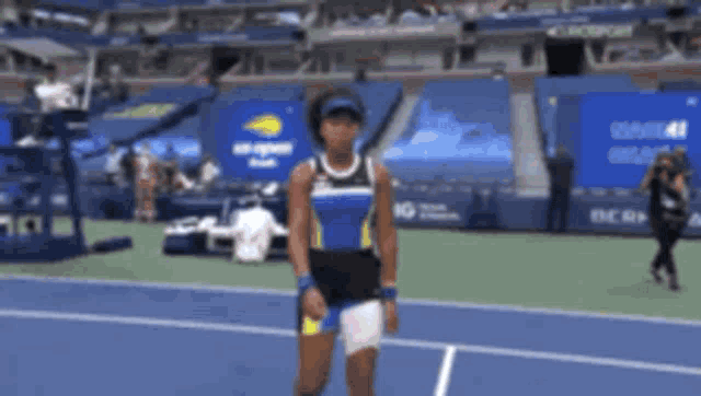 a woman is standing on a tennis court wearing a blue and black outfit