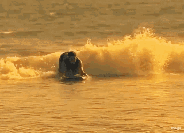 a man is riding a wave on a surfboard in the ocean with the watermark rdd.gif