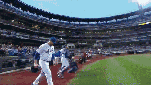 a baseball player wearing a mets jersey walks off the field during a game