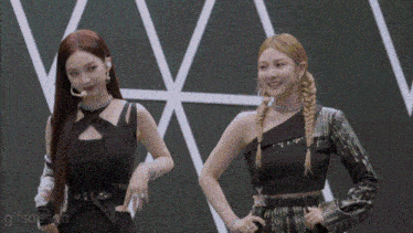 two women standing next to each other with their hands on their hips