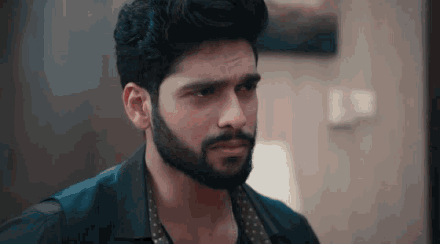 a man with a beard wearing a black shirt and polka dot vest