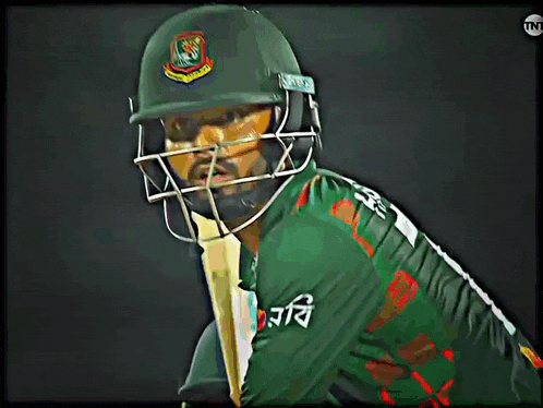 a cricket player wearing a helmet with the letters tnt on the bottom left
