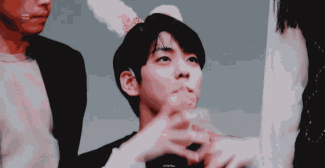 a young man wearing bunny ears is being photographed by another man