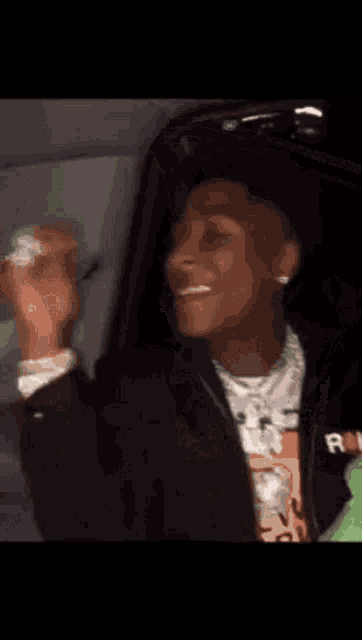 a man is sitting in the back seat of a car with his arms outstretched .