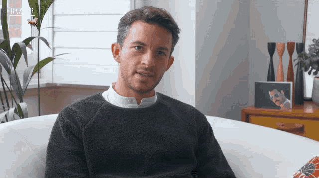 a man in a grey sweater sits in a chair with the word harper on the bottom