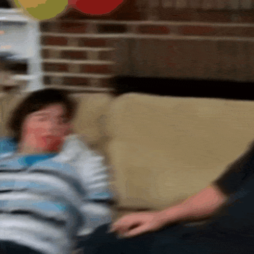 a blurry picture of a person sitting on a couch with balloons in the background
