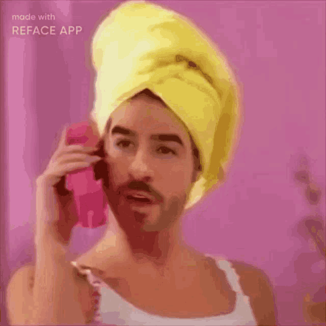 a man with a yellow towel on his head is talking on a pink phone .