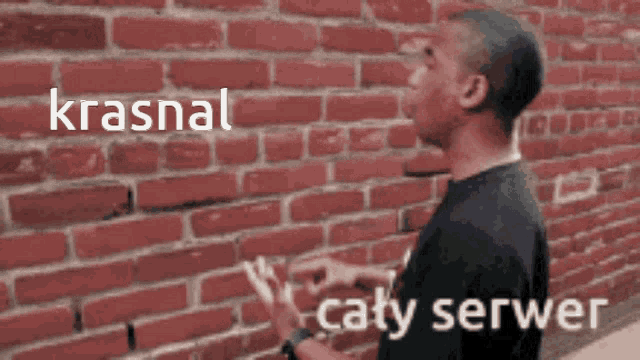 a man standing in front of a brick wall with the words krasnal caty serwer
