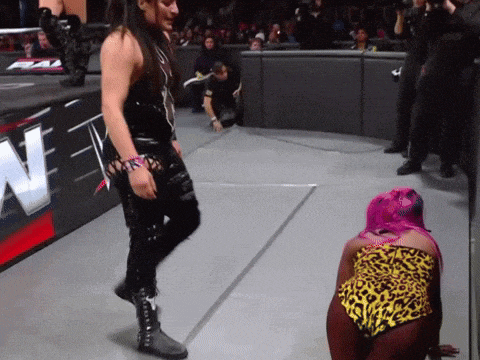 a woman with pink hair is kneeling on the ground in front of a sign that says n