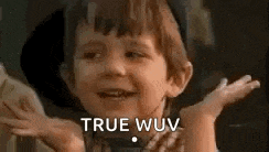 a little boy is making a funny face and saying `` true wuv '' with his hands in the air .