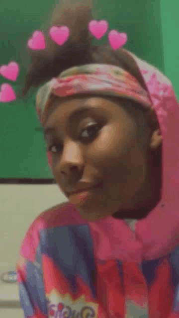 a girl wearing a headband with pink hearts on it looks at the camera .