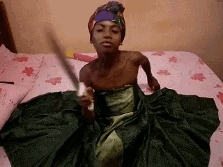 a woman sitting on a bed holding a sword