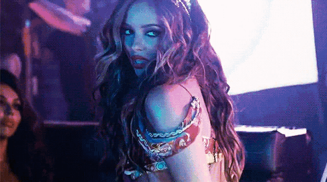 a woman with long hair is standing in a dark room in a costume .