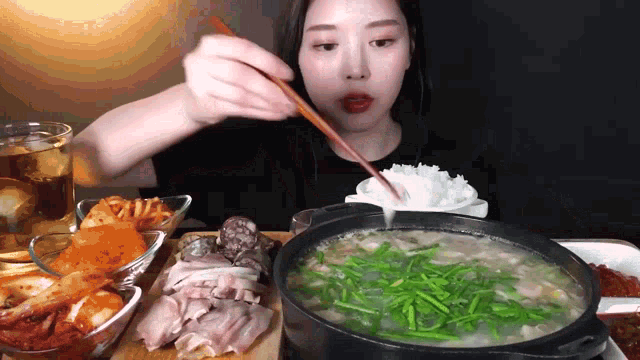 a woman is eating soup with chopsticks and rice