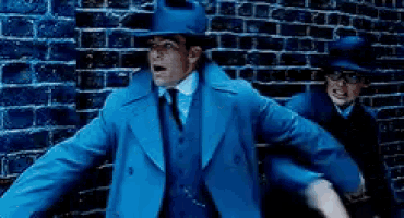 a man in a blue coat and hat is standing next to another man in a black hat .