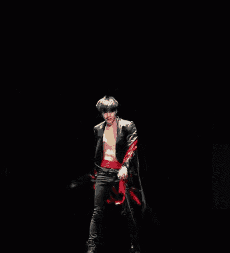 a man without a shirt is dancing with red ribbons around his waist .