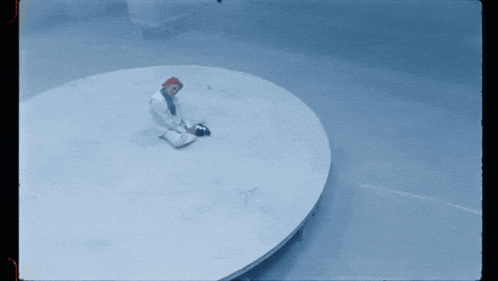 a man in a red hat sits in a circle in a blue room