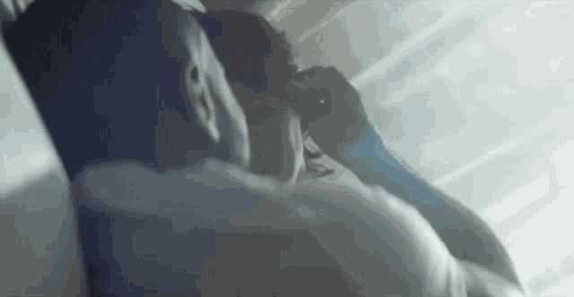 a man is touching a woman 's hair while they are laying in bed .