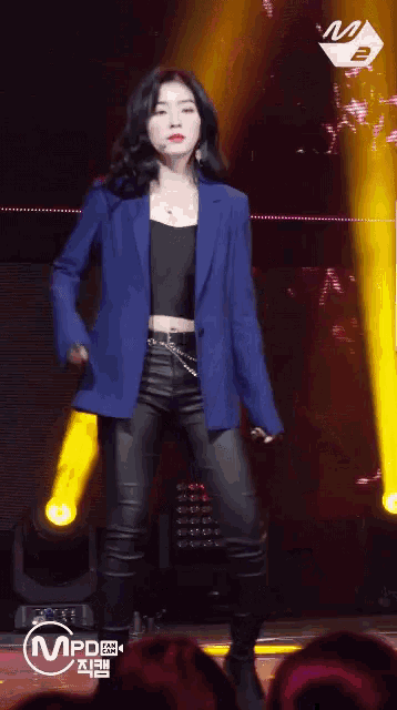 a woman in a blue jacket is dancing on a stage with a mvpd logo in the background