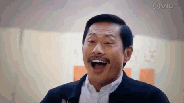 a man with a mustache is laughing with his mouth open in front of a sign that says viutv