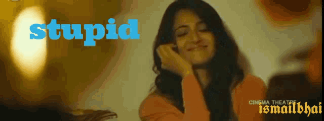 a woman is smiling in front of a poster that says stupid