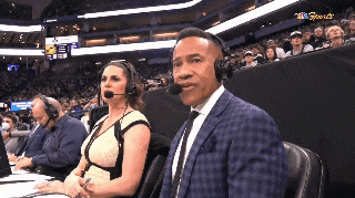 a man and a woman wearing headphones are watching a basketball game on abc