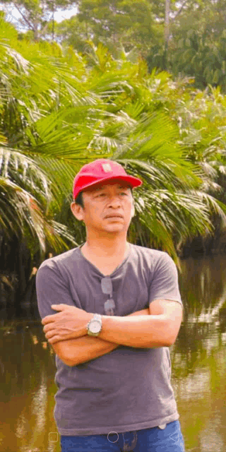 a man wearing a red hat is standing in front of a river