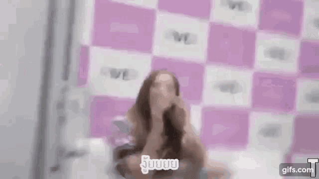 a blurry picture of a woman laying on a bed in front of a pink wall .