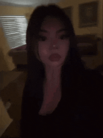 a woman with long dark hair is standing in a living room in the dark .