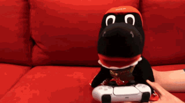 a stuffed animal wearing a red hat with the letter c on it is sitting on a red couch
